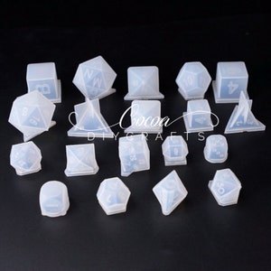 May include: A set of 15 clear silicone molds for making dice. The molds are in various shapes, including cubes, pyramids, and dodecahedrons. The molds are designed to create dice with numbers 1 through 20.