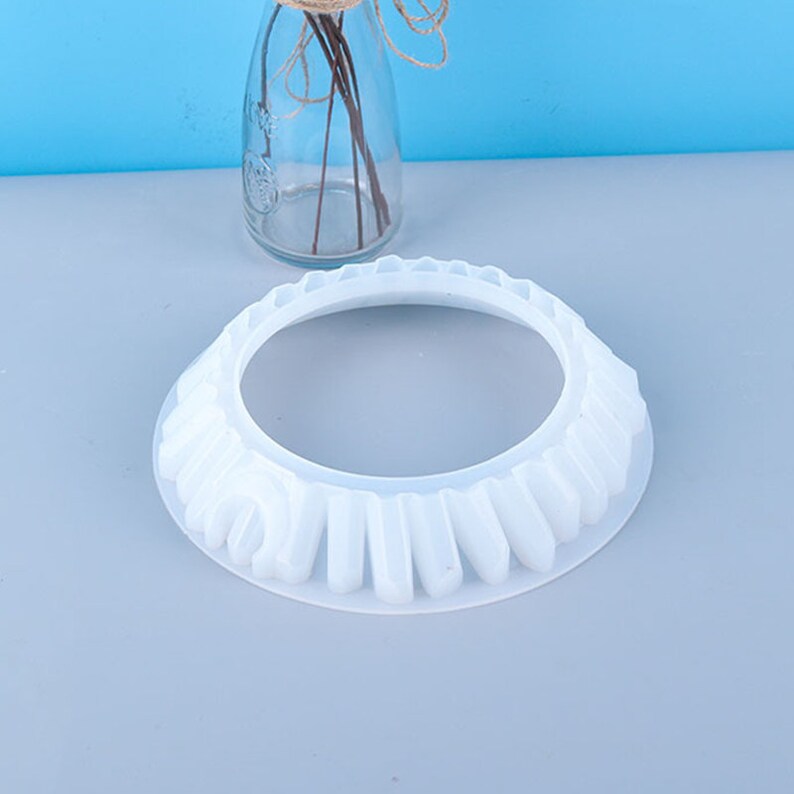 May include: White silicone cake mold with a fluted edge and a round center. The mold is designed to create a cake with a decorative edge.