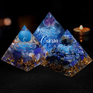 May include: Three crystal pyramids with blue and purple crystals inside. The pyramids are made of clear resin and have gold flakes embedded in the resin. The text "Cocoa DIY Crafts" is visible on the image.