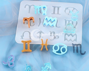 May include: A white silicone mold with 12 zodiac signs. The mold is filled with blue and brown resin zodiac charms.