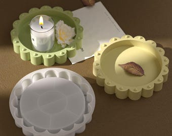 May include: Three decorative trays in shades of green and yellow. One tray holds a lit candle and a flower, another has a leaf, and the third is a mold. Each tray has a scalloped edge. The background is a neutral brown.