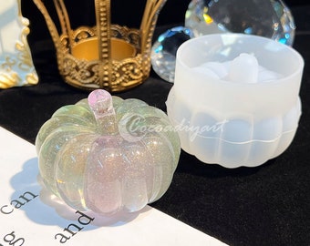 May include: A clear, iridescent pumpkin-shaped resin mold with a pink stem. The mold is sitting on a white surface with text that reads "can rd; and ing".