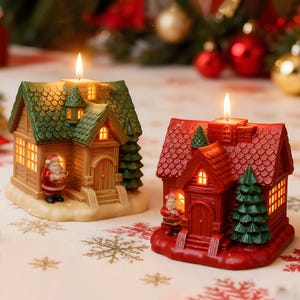 May include: Two Christmas house candles. One is brown and green, the other is red. Each has a lit candle on top, a Santa figurine, and a small Christmas tree. The houses have lit windows.