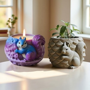 Puede incluir: Un portavelas con temática de ardilla azul y morado con una vela encendida y una maceta de ardilla gris con una planta. El portavelas tiene un diseño detallado y la maceta tiene una superficie texturizada.