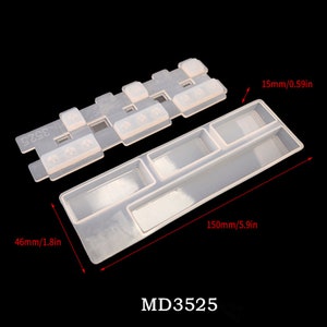 May include: A clear silicone mold for making resin keycaps. The mold has 10 individual cavities for creating different sized keycaps. The mold is 5.9 inches long and 1.8 inches wide. The mold is labeled "MD3525".