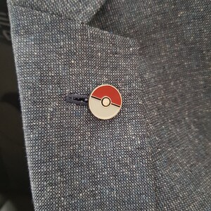 May include: A red and white Pokeball pin on a blue blazer.
