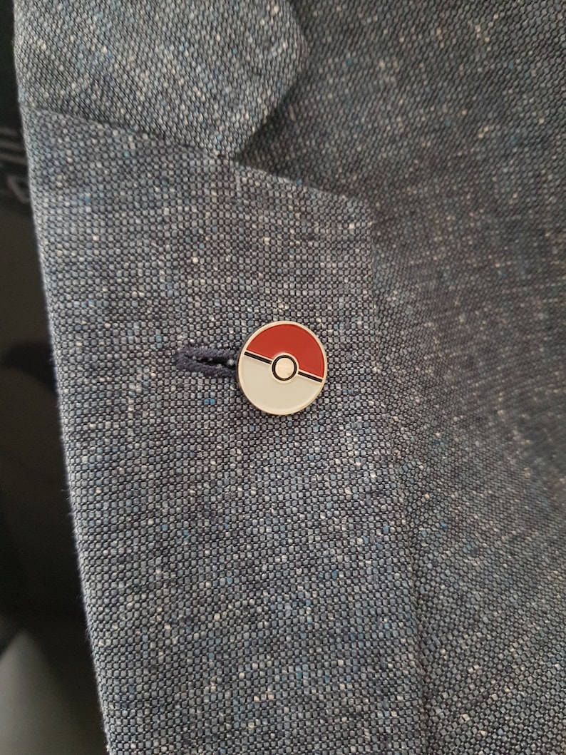 May include: A red and white Pokeball pin on a blue blazer.