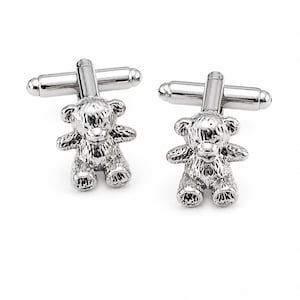 Può includere: Un paio di gemelli in metallo color argento con un design a forma di orsetto tridimensionale. Ogni gemello presenta una finitura lucida con dettagli testurizzati sul pelo, sulle orecchie e sulle zampe, fissati a una chiusura girevole.