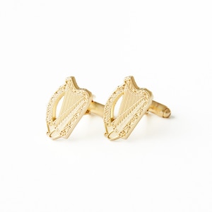 May include: A pair of gold cufflinks featuring a detailed design of a Celtic harp.