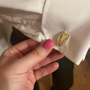 May include: Gold cufflinks featuring a detailed design of a harp, a traditional Irish symbol.