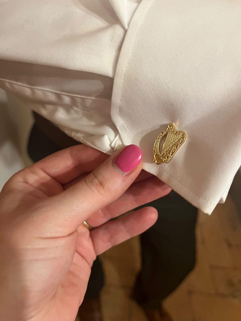 May include: Gold cufflinks featuring a detailed design of a harp, a traditional Irish symbol.