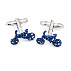 Könnte beinhalten: Ein Paar Manschettenknöpfe mit einem blauen Fahrradmotiv. Jeder Manschettenknopf hat eine metallisch blaue, fahrradförmige Vorderseite mit einem silberfarbenen Knebelverschluss. Das Fahrrad-Design umfasst Rahmen, Sattel, Lenker und zwei Räder.