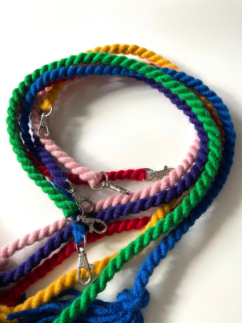 May include: A set of six colorful, braided cotton ropes with silver clasps. The ropes are in shades of blue, green, yellow, red, and pink.