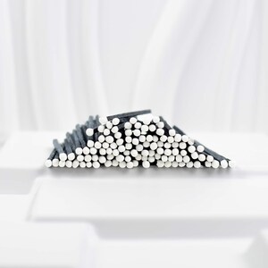 May include: A close-up of a pile of black and white matches. The matches are arranged in a wave-like pattern, with the white tips of the matches facing the viewer.