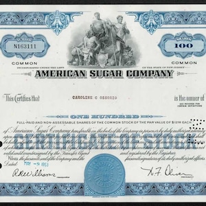 May include: An antique stock certificate from the American Sugar Company, featuring a blue and white design. The certificate is for 100 shares and includes the name Caroline C. Ossorio. Dated May 19, 1953.