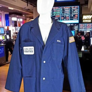 May include: A navy blue jacket with white buttons, two front pockets, and a Global Direct Equities patch. The name "MIKE" is embroidered on the right chest. An American flag patch is on the right sleeve. The jacket is displayed on a mannequin.