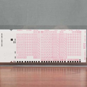 May include: A clear plastic card holder with a white card inside. The card has a grid of small pink circles and the text "POST 12 BOOK 11 CARD 13041 MDS".