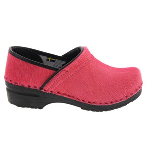 Op de afbeelding: Roze wollen klompen met een zwarte zool en een Zweedse vlag aan de binnenkant.