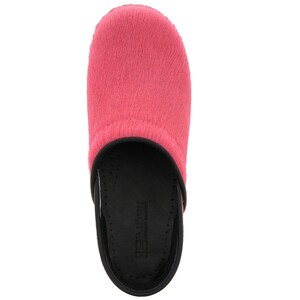 Op de afbeelding: Roze pluche clog met een zwarte zool en het woord "Birkenstock" gedrukt op de zool.