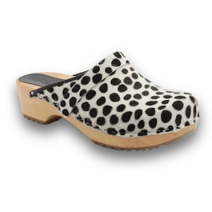 May include: Black and white spotted clogs with a wooden heel and sole.