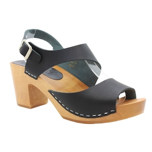 Op de afbeelding: Zwarte leren peeptoe sandalen met hak, houten platform en een gespsluiting aan de enkel.