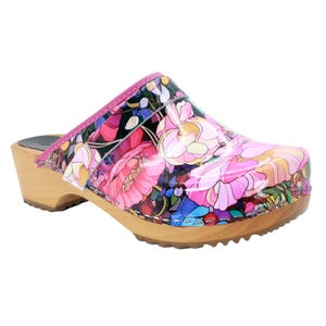 May include: A pair of wooden clogs with a floral print. The clogs have a pink and black floral pattern with a wooden heel and sole.