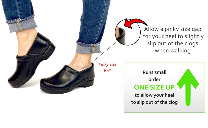 Op de afbeelding: Zwarte leren klompen met een houten hak. De afbeelding toont een persoon die de klompen draagt en een notitie dat de schoenen klein uitvallen en dat je een maat groter moet bestellen om te zorgen dat de hiel uit de klomp kan glijden tijdens het lopen.