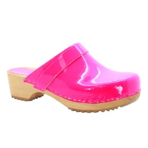 May include: A bright pink clog with a glossy finish. The shoe features a wooden sole and a strap across the top. The stitching is white, and the overall design is simple and stylish.