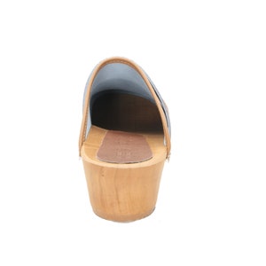 May include: A pair of blue suede clogs with a wooden heel and a brown leather insole.