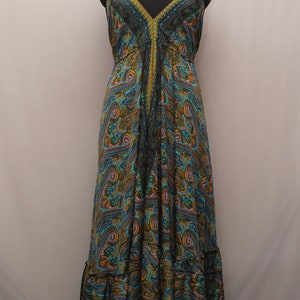 Może przedstawiać: Długa, zwiewna sukienka maxi z wzorem paisley w odcieniach niebieskiego, zielonego i złotego. Sukienka ma dekolt halter i warstwową spódnicę.