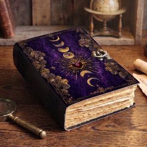 Peut inclure: Un journal rectangulaire avec une couverture violette profonde ornée d'un motif de phases lunaires dorées, d'un emblème central en forme de cœur et de bordures en filigrane doré. Le livre possède une fermeture à loquet et des pages épaisses.