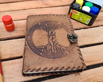 Op de afbeelding: Een bruin leren dagboek met een levensboomontwerp en een metalen sluiting. Het dagboek heeft een Keltisch knoopontwerp rond de boom en twee figuren die elkaar omhelzen in de boom.