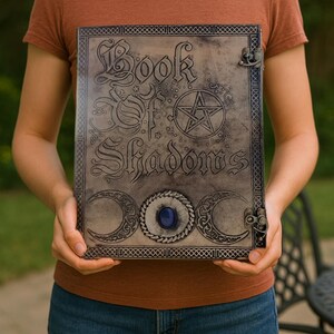 May include: A leather-bound journal with a pentagram and the words "Book of Shadows" embossed on the cover. The journal has a blue gemstone and a metal clasp.