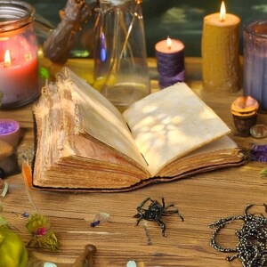 May include: An open, aged book with blank pages sits on a wooden table, surrounded by candles, jars, and a decorative spider. The scene evokes a mystical or magical theme, with warm lighting and various small objects.