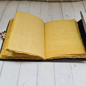 May include: A yellow leather-bound journal with a brass clasp. The journal is open to reveal blank pages.