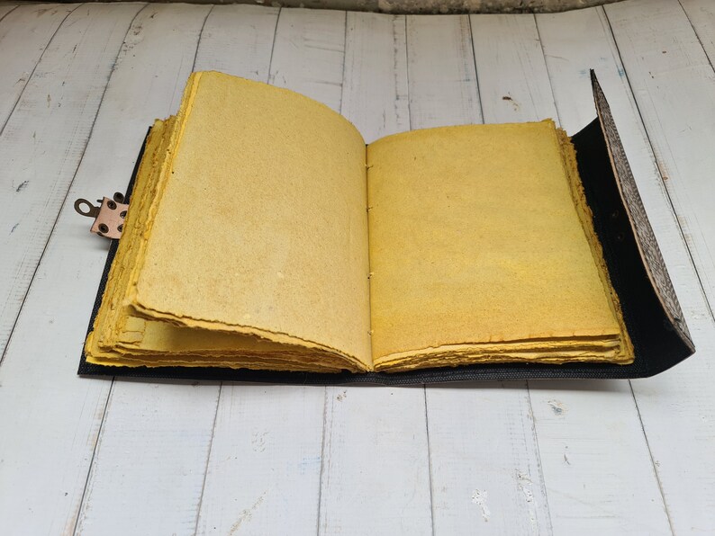 May include: A yellow leather-bound journal with a brass clasp. The journal is open to reveal blank pages.
