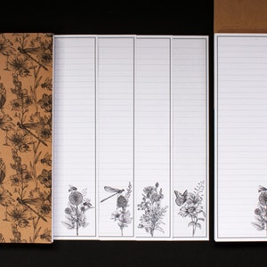 May include: Set of five lined notepads with a brown kraft paper cover featuring a floral and insect design. The notepads have a white background with black lines and a floral design at the bottom.