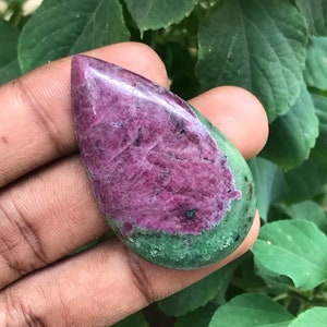 以下が含まれることがあります： 涙の形をした緑とピンクの宝石のカボション。石は滑らかで磨かれた表面を持ち、ピンクのアクセントのある鮮やかな緑色をしています。