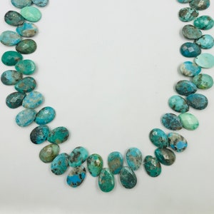 Peut inclure: Un brin de perles de turquoise, chaque perle est de forme ovale unique avec une couleur bleu et vert marbrée.