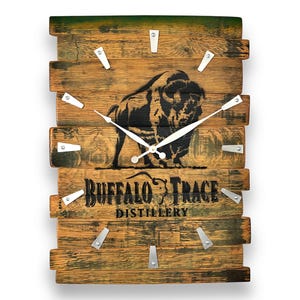 May include: Wooden wall clock with a rustic design. The clock features a black silhouette of a bison and the text "Buffalo Trace Distillery." The clock hands are white, and the hour markers are silver. The clock is made of wooden planks.