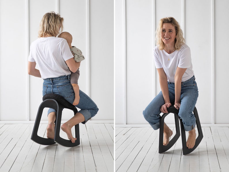 Puede incluir: Una mujer se sienta en una silla mecedora negra con un asiento curvo y una base ancha. Lleva pantalones vaqueros azules y una camiseta blanca. En la otra imagen, la mujer est&aacute; sentada en la misma silla, pero no est&aacute; sosteniendo un beb&eacute;.