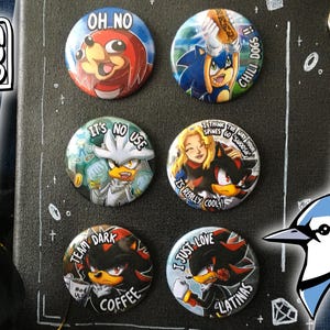 Op de afbeelding: Een set van acht ronde knoopsluitingen met verschillende personages uit de Sonic the Hedgehog-videogameserie. De knoopsluitingen zijn kleurrijk en bevatten verschillende personages, waaronder Sonic, Shadow en Silver. De knoopsluitingen zijn gerangschikt in een rasterpatroon op een zwart oppervlak.