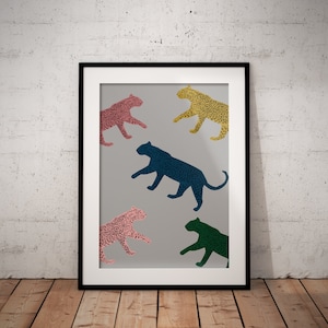 May include: Framed art print with five leopard illustrations in pink, yellow, green, and blue on a grey background. The leopards are in a walking pose. The print is in a black frame, set against a wooden floor.