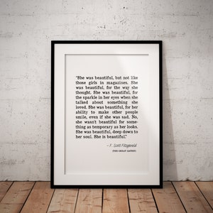 May include: A black and white framed print featuring a quote from F. Scott Fitzgerald's "The Great Gatsby" about the beauty of a person's soul. The quote reads, "She was beautiful, but not like those girls in magazines. She was beautiful, for the way she thought. She was beautiful, for the sparkle in her eyes when she talked about something she loved. She was beautiful, for her ability to make other people smile, even if she was sad. No, she wasn't beautiful for something as temporary as her looks. She was beautiful, deep down to her soul. She is beautiful."