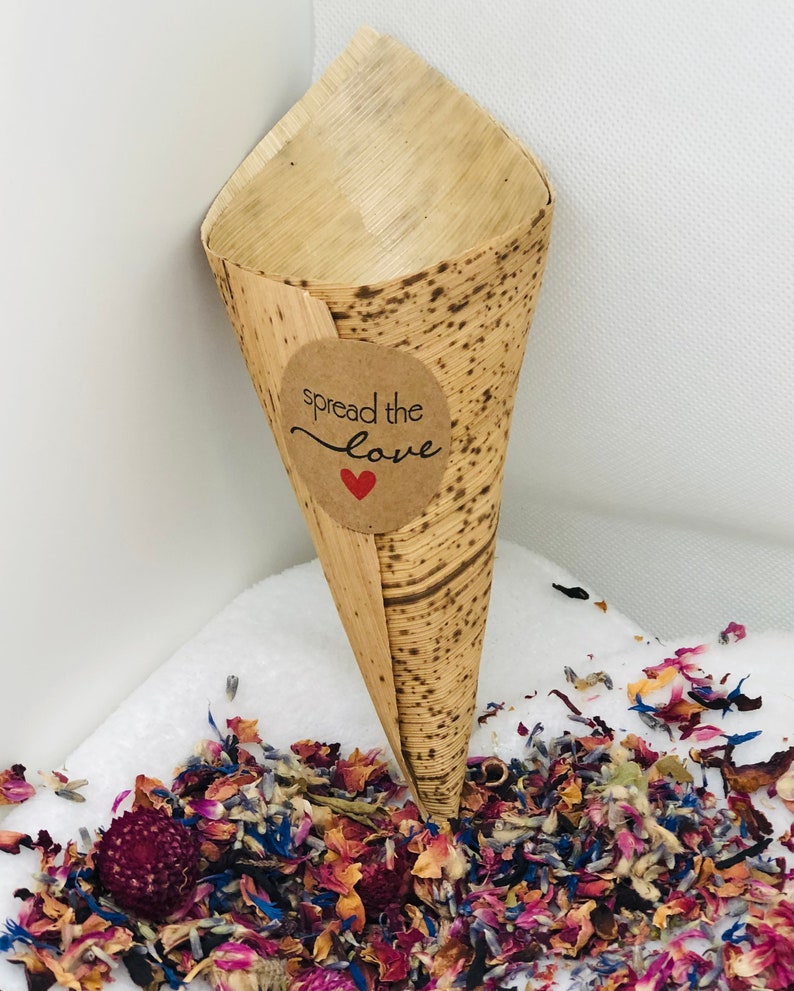 May include: A brown paper cone with a sticker that says "spread the love" with a red heart. The cone is filled with colorful flower petals.