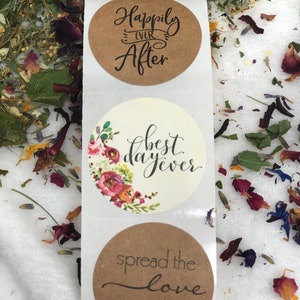 May include: Three round kraft paper stickers with wedding-themed text. The top sticker says "Happily Ever After". The middle sticker has a floral design and says "best day ever". The bottom sticker says "spread the love" with a red heart.