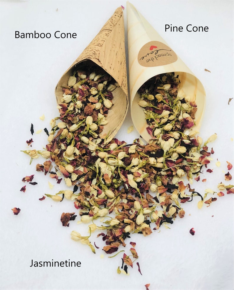 May include: Two bamboo cones filled with dried jasmine and rose petals. The cones are labeled "Bamboo Cone" and "Pine Cone". The text "Spread the Love" is printed on the pine cone. The petals are scattered on a white surface with the text "Jasminetine" printed below.