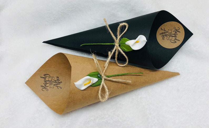 May include: Two wedding favor cones, one brown and one black, with white calla lilies and twine bows. The brown cone has a sticker that says "Happily Ever After".