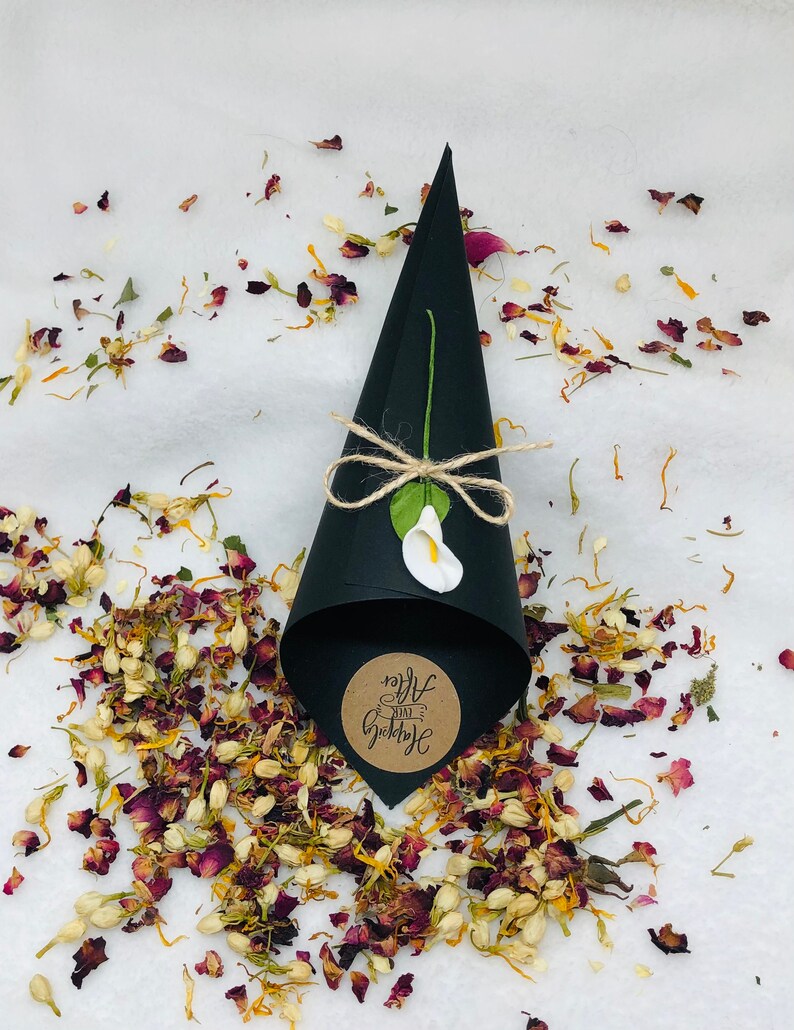 May include: Black paper cone filled with dried flower petals for a wedding ceremony. The cone has a brown paper circle attached with the text "Just Married" written in white.