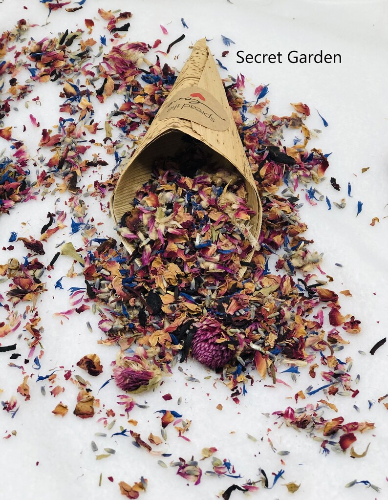 May include: A paper cone filled with dried flower petals in shades of pink, purple, blue, and brown. The cone is labeled "Secret Garden".